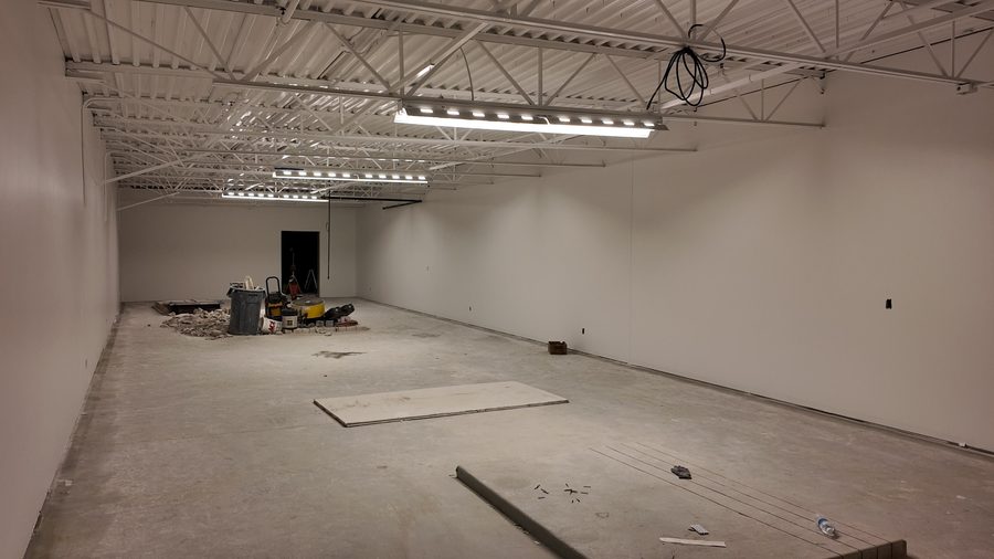 A large open commercial room with white walls and an exposed ceiling