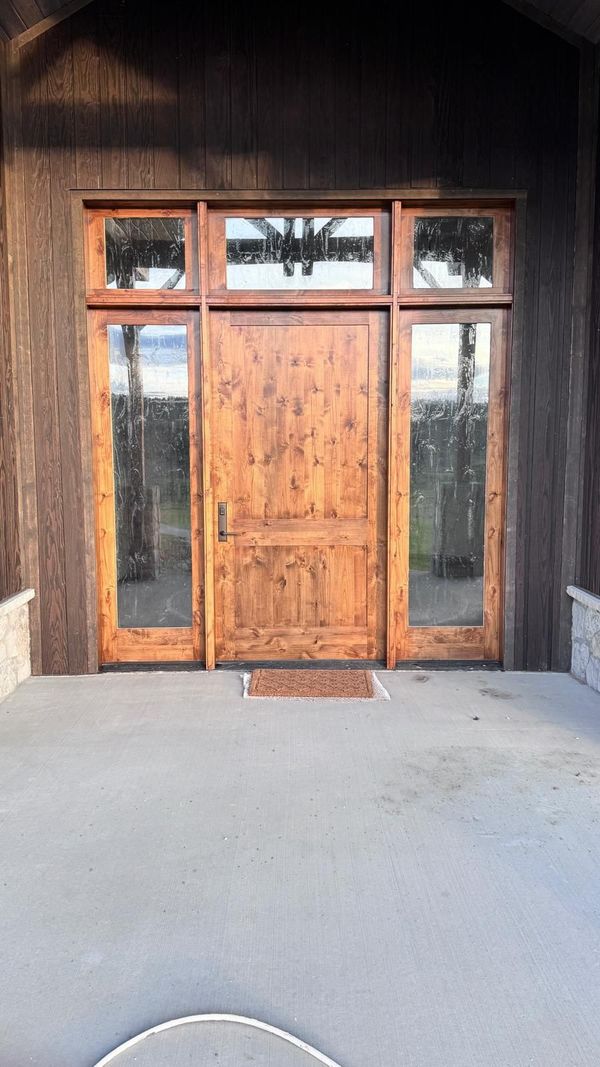 A stained wood front door with sidelights and transom windows