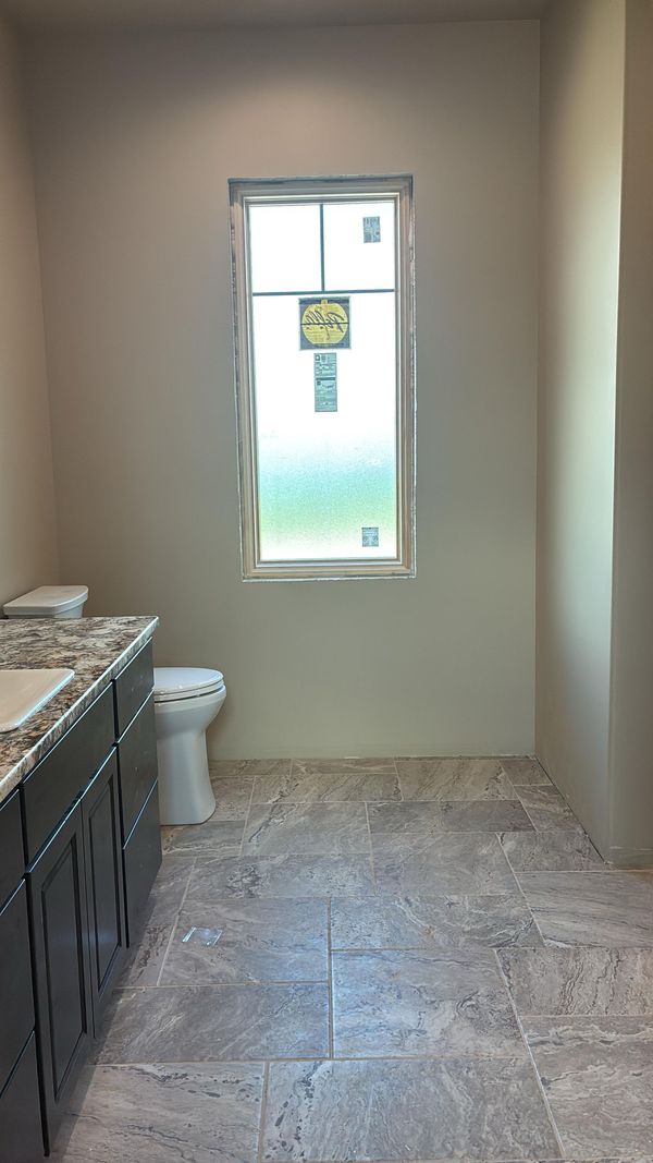 A bathroom with fresh paint, a tiled floor and a frosted window
