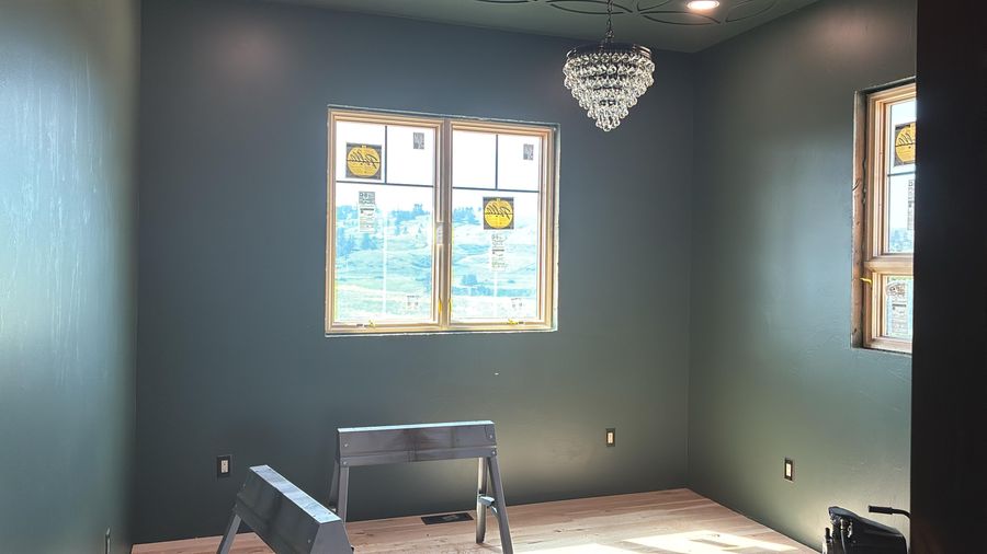 A bedroom painted dark green with a crystal chandelier