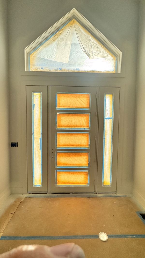 A front door with a glass panel and a peaked transom, seen from inside