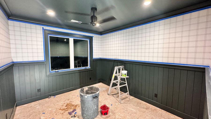 A room with dark green wainscoting and patterned upper walls