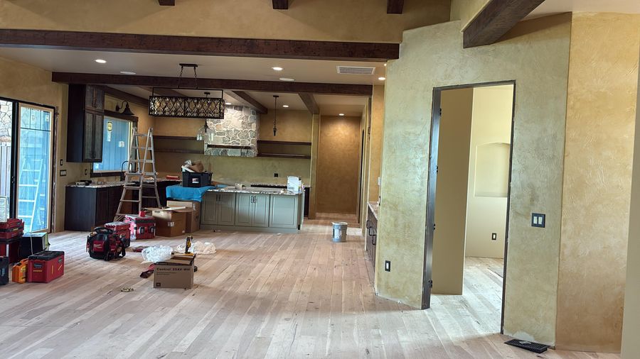 An open living room and kitchen with plaster-finish walls and timber beams