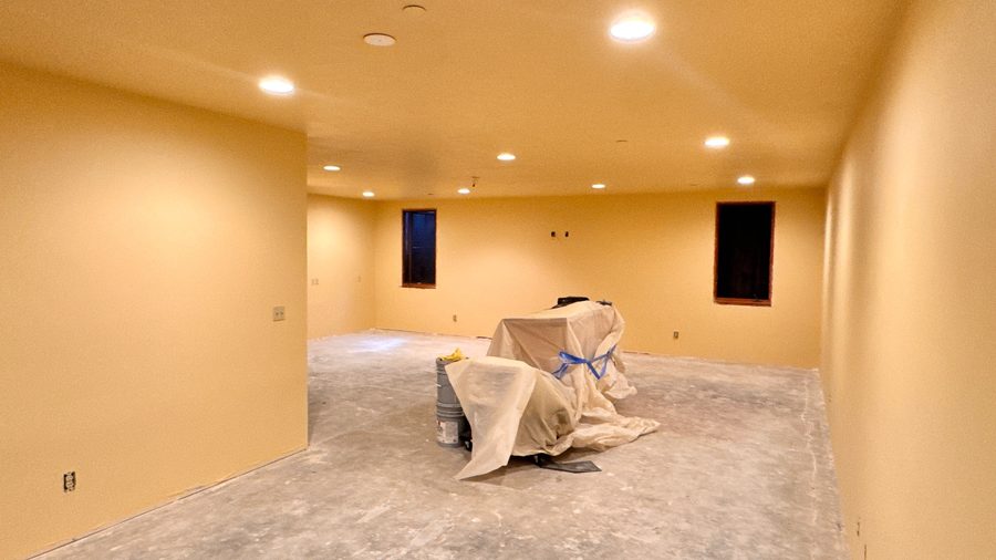 A lower level room painted warm amber with recessed lights