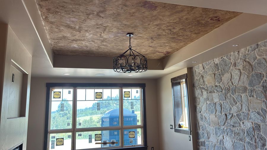 A tray ceiling with a textured finish beside a stone wall