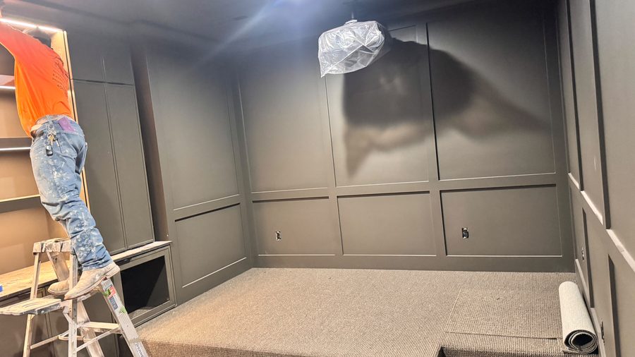 A painter spraying a panelled room from a ladder